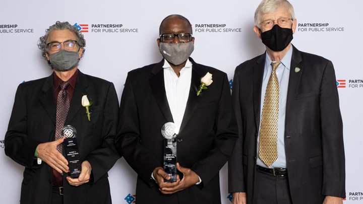 Eliseo Pérez-Stable and Gary Gibbons hold awards. Francis Collins stands next to them.