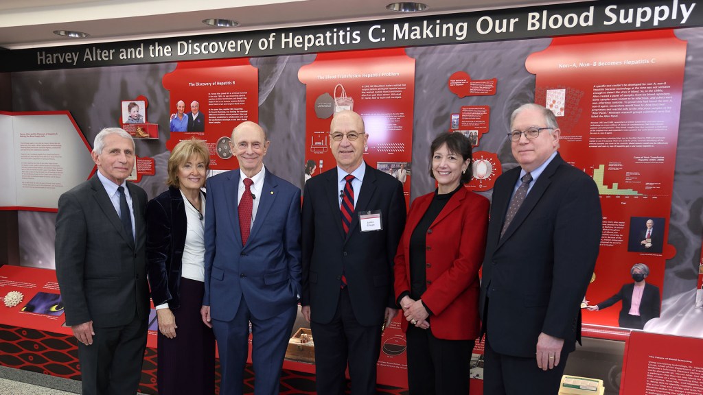 Harvey Alter and the Discovery of Hepatitis C: Making Our Blood Supply Safe. A group of four men and two women stand in front of the exhibit