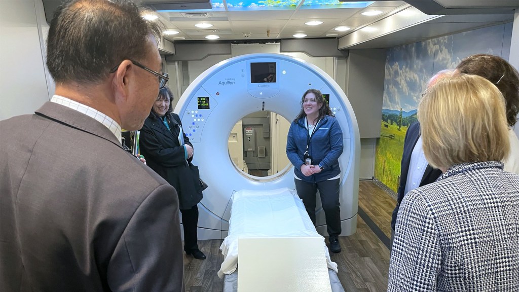 Several people stand around a medical scanning unit